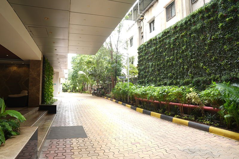Landscaped arrival drive running the length of the building, with a planted green wall alongside.