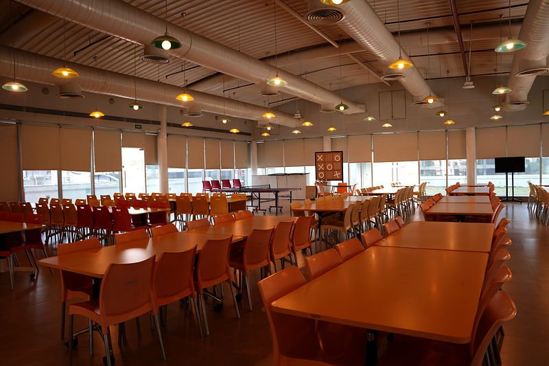 Fifth floor cafeteria with long communal tables and windows on three sides.