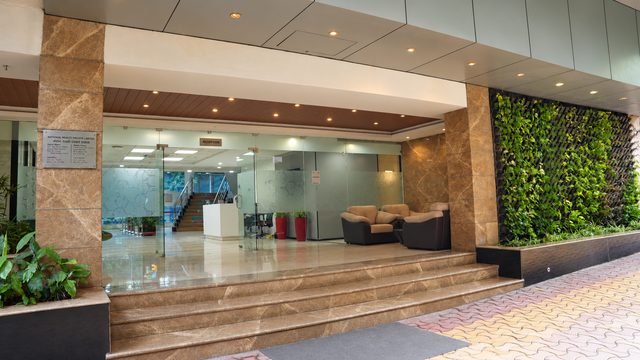 Main entrance in stone and glass, with a living green wall beside the reception doors.