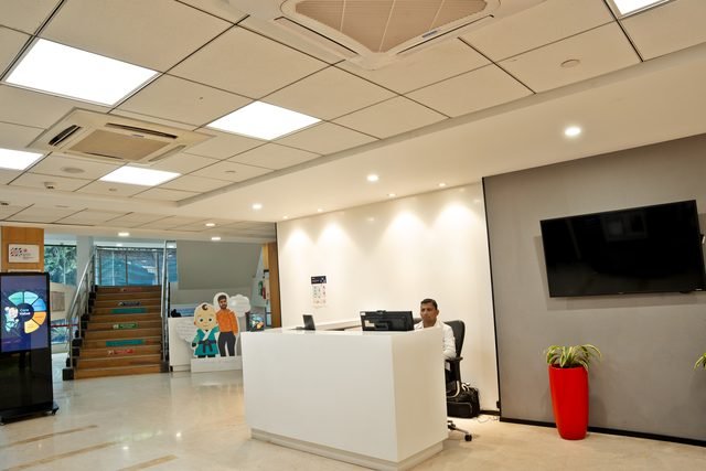 Staffed ground floor reception desk with digital display and the main stair behind.