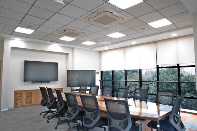 Boardroom seating fourteen, with dual displays and a green outlook.